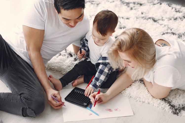 man and woman drawing hearts with their child